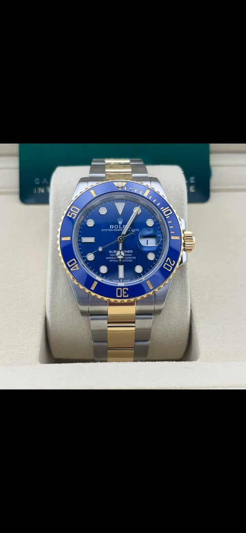 Rolex Submariner watch with blue dial and two-tone stainless steel and gold bracelet displayed on white watch pillow