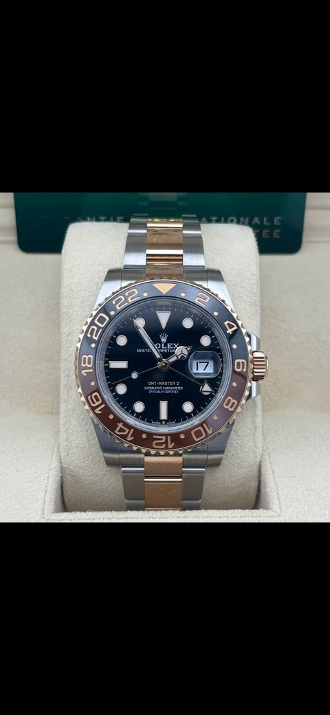 Rolex GMT-Master II watch with two-tone steel and rose gold bracelet displayed on white pillow with Rolex box in background