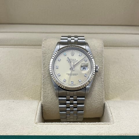Silver Rolex watch with white dial on beige fabric stand